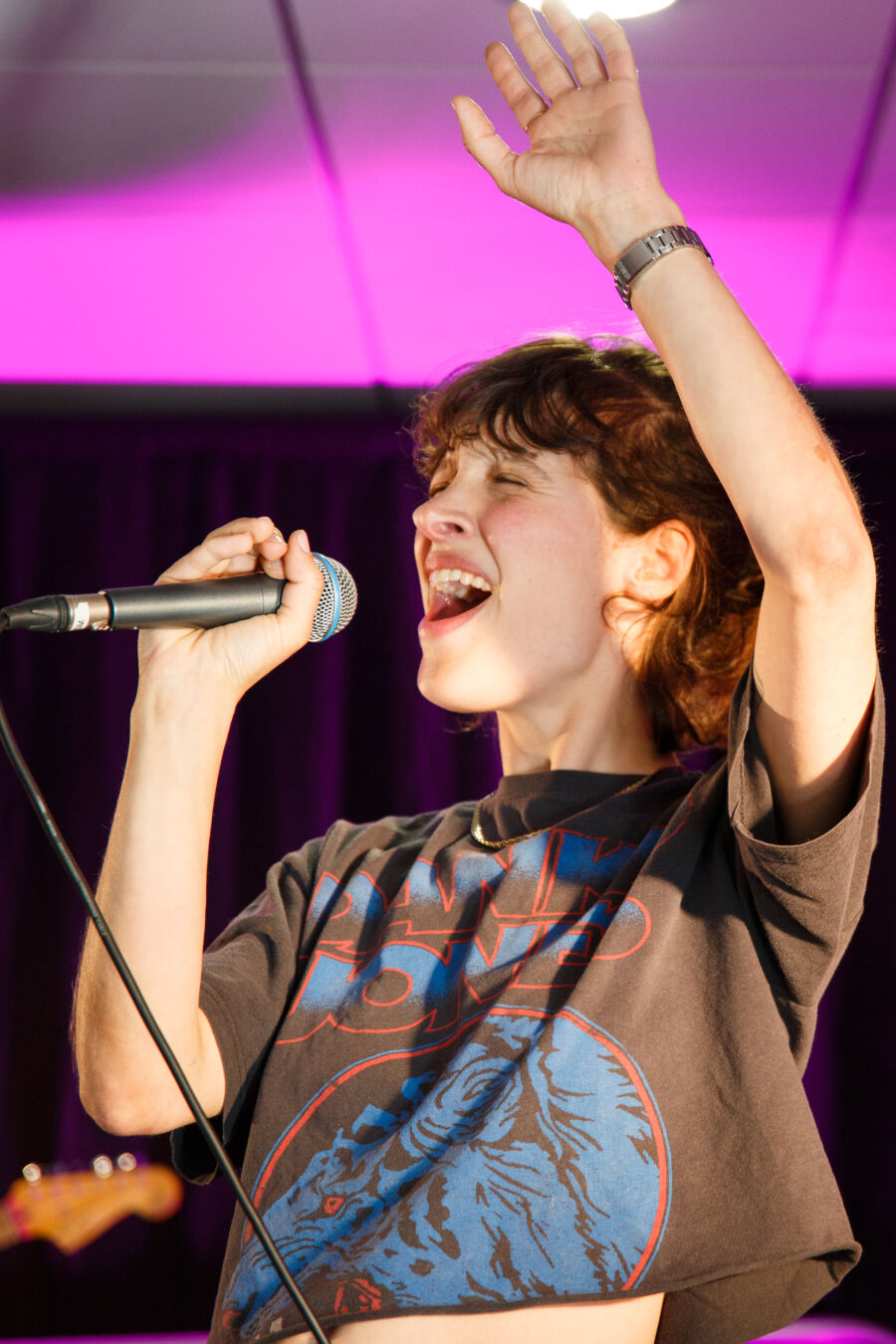 close up picture of the eyes-closed singer raising her hand