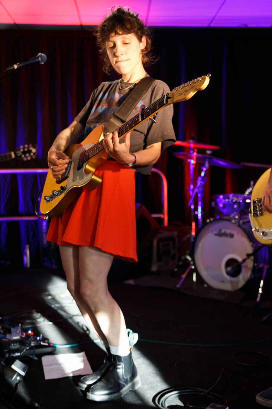 singer with a red skirt and black tee-shirt playing guitar