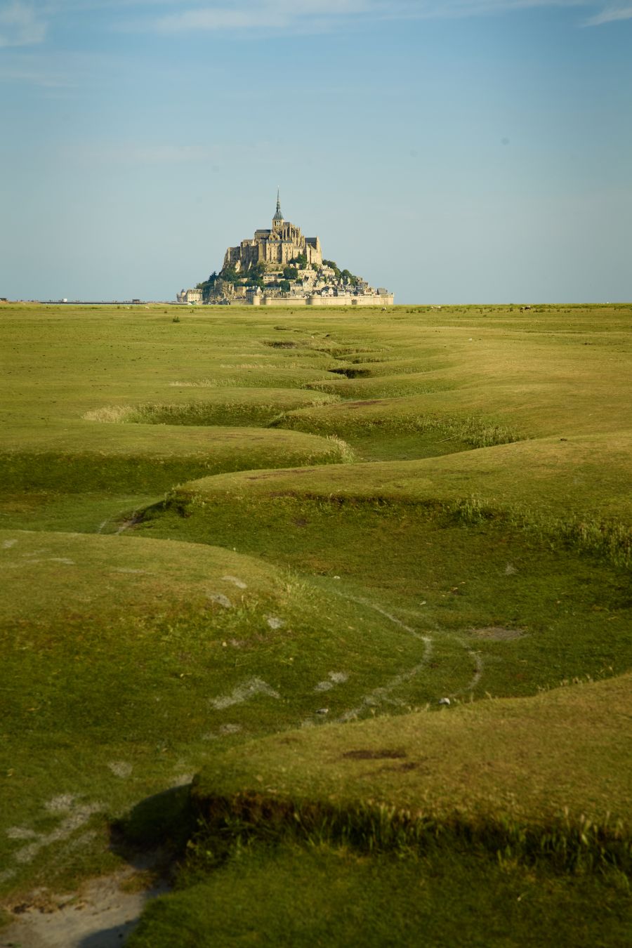 Vue sur le Mont Saint Michel depuis la plaine. Les méandres au premier plan guident le regard vers le mont en arrière plan