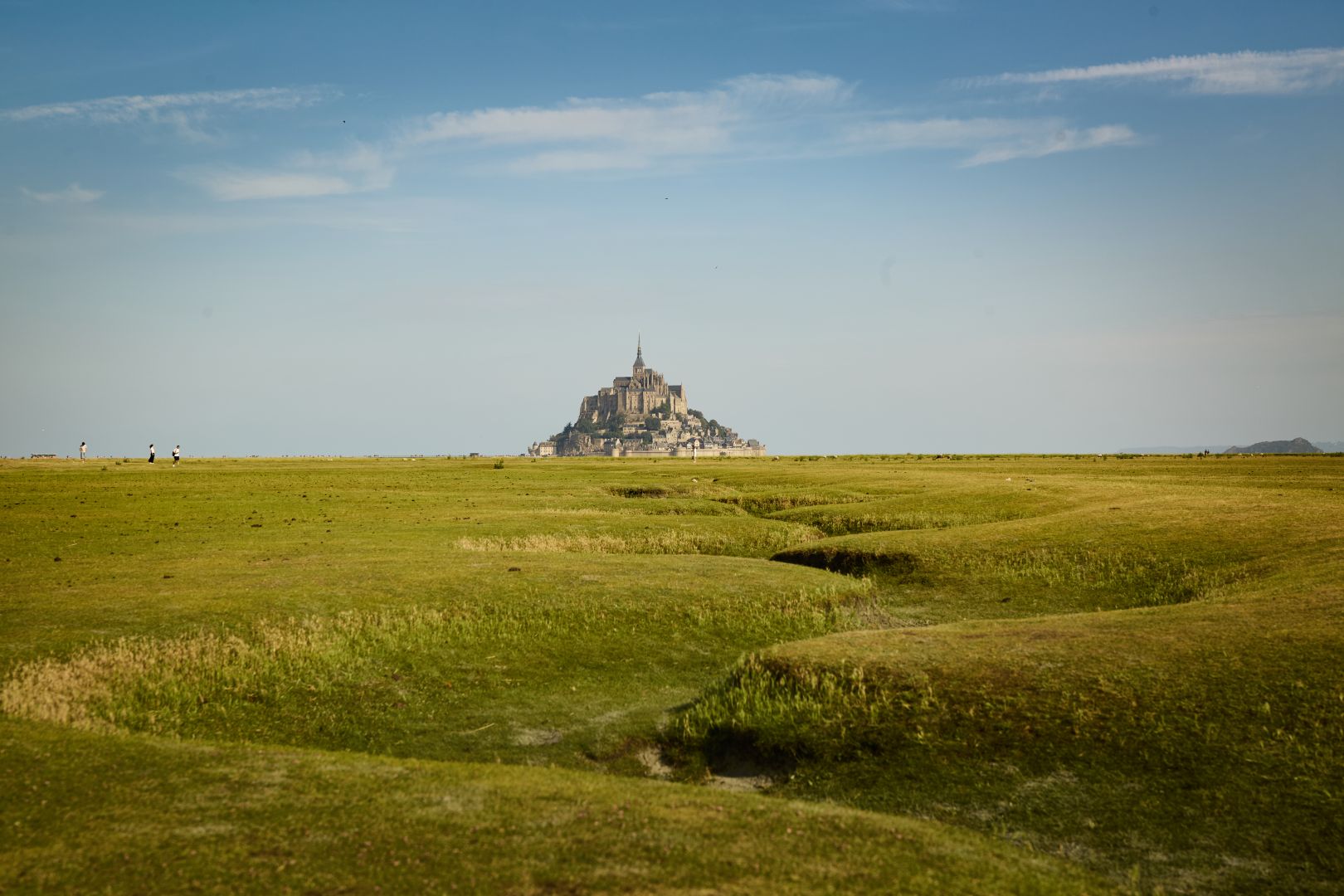 Vue sur le Mont Saint Michel depuis la plaine. Les méandres au premier plan guident le regard vers le mont en arrière plan
